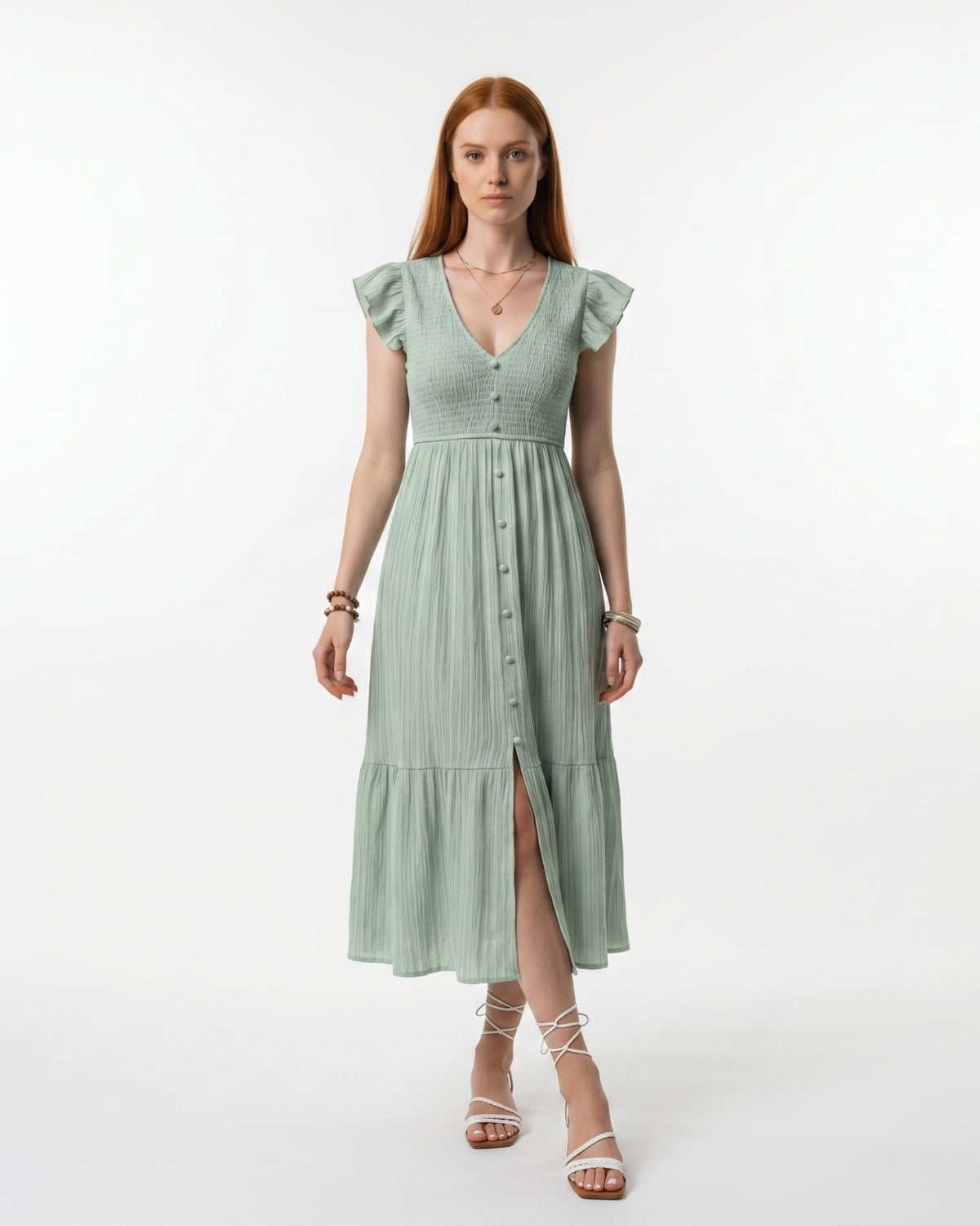 Woman wearing a light green dress with ruffled sleeves on a white background
