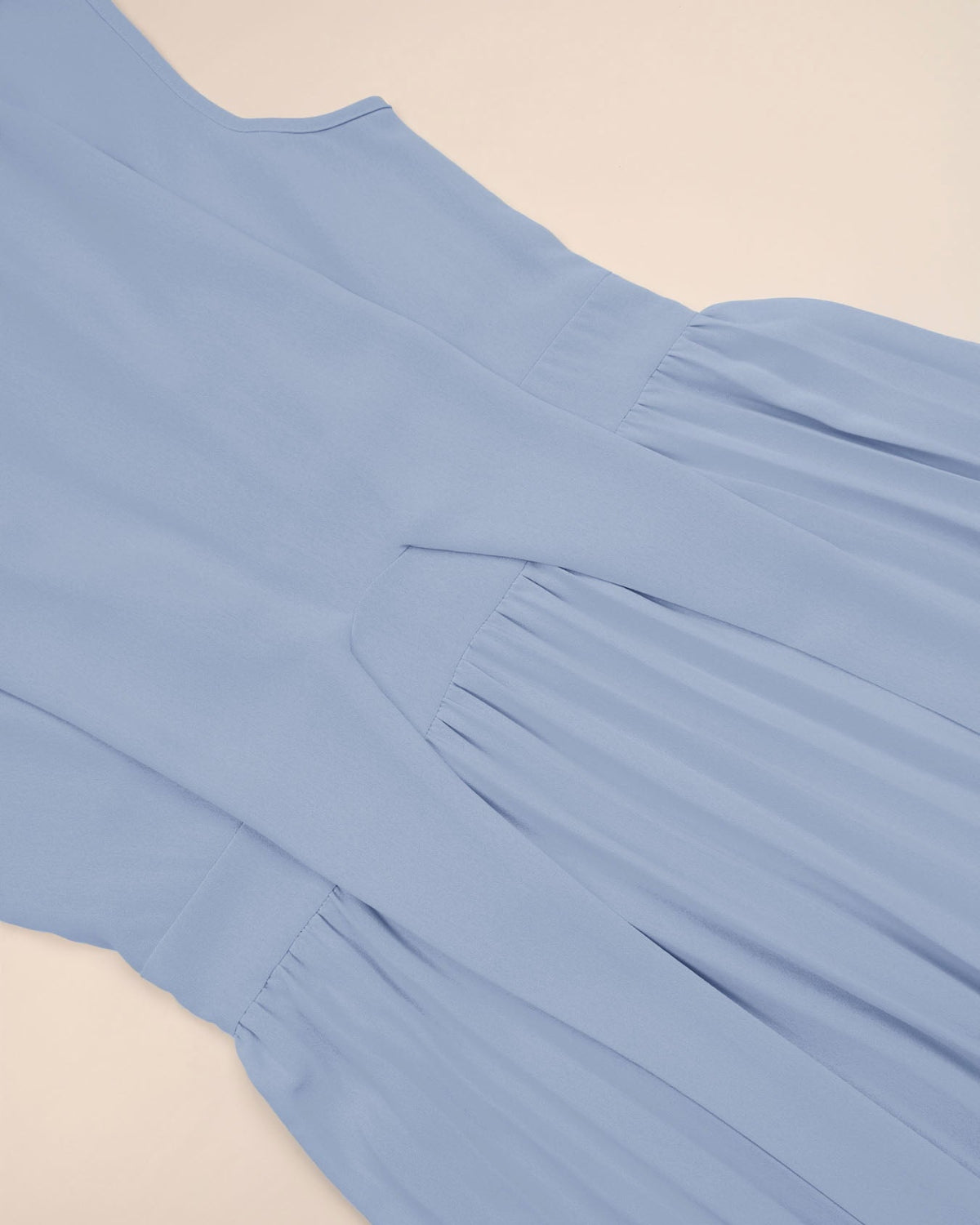 Light blue dress with pleated details on a beige background