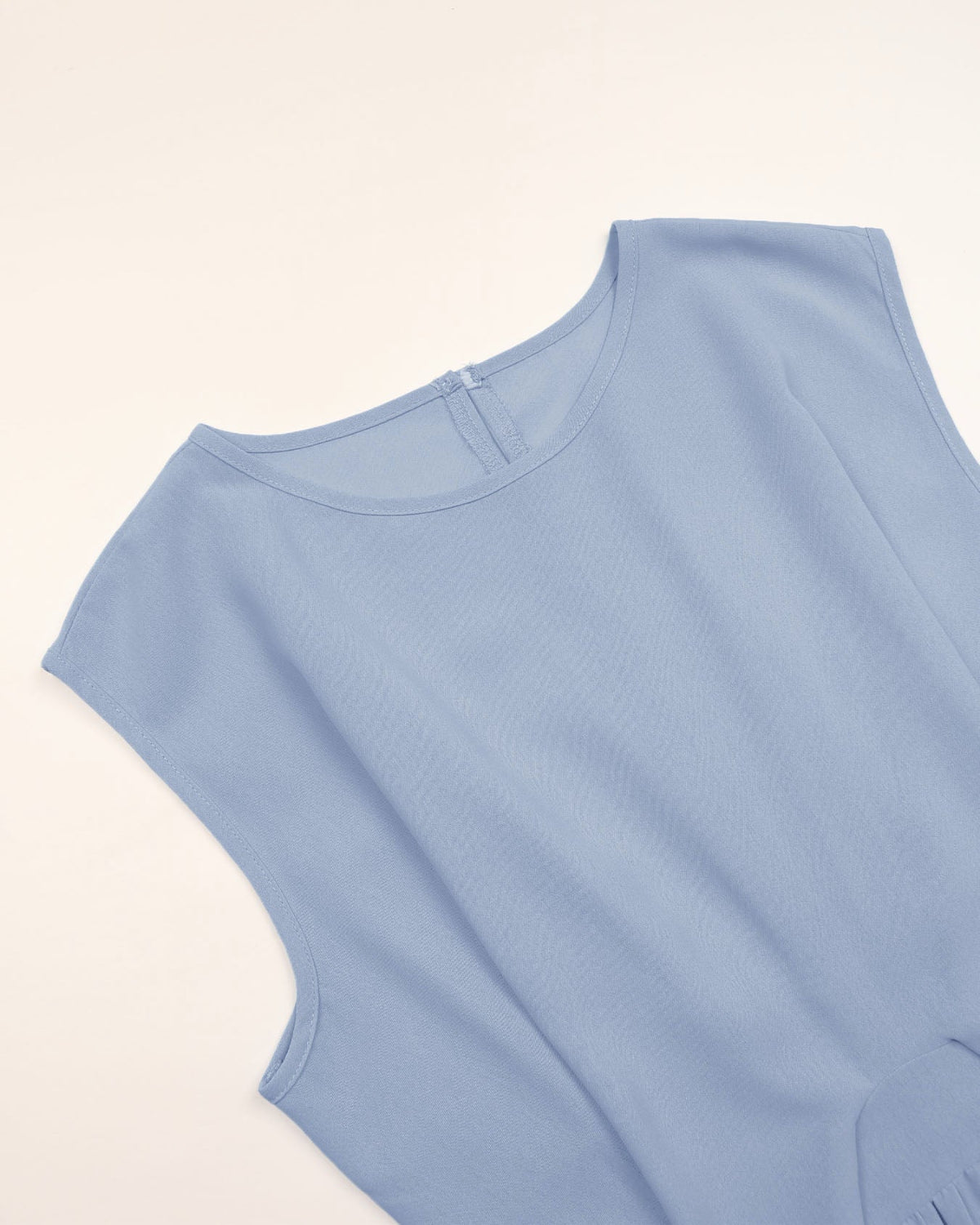 Light blue sleeveless top on a beige background