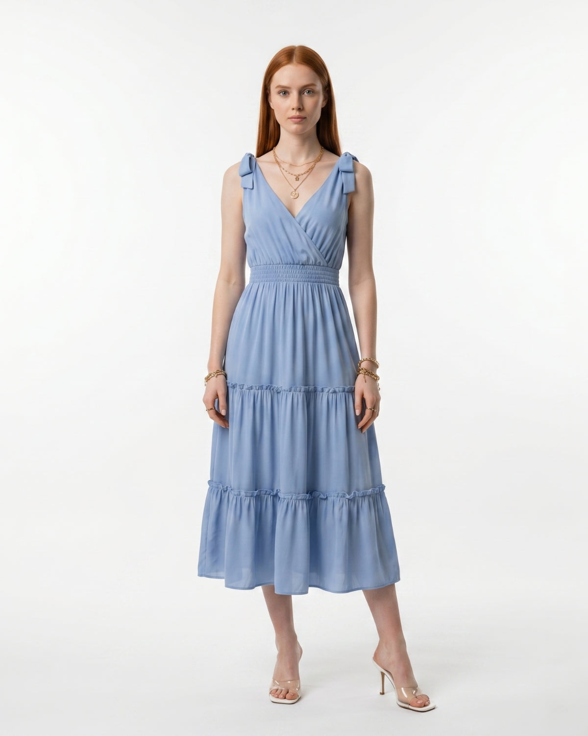 Woman wearing a light blue dress with ruffled straps on a white background