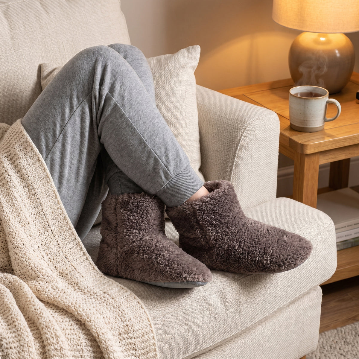 Woman relaxing on a sofa in coffee fleece bootie slippers