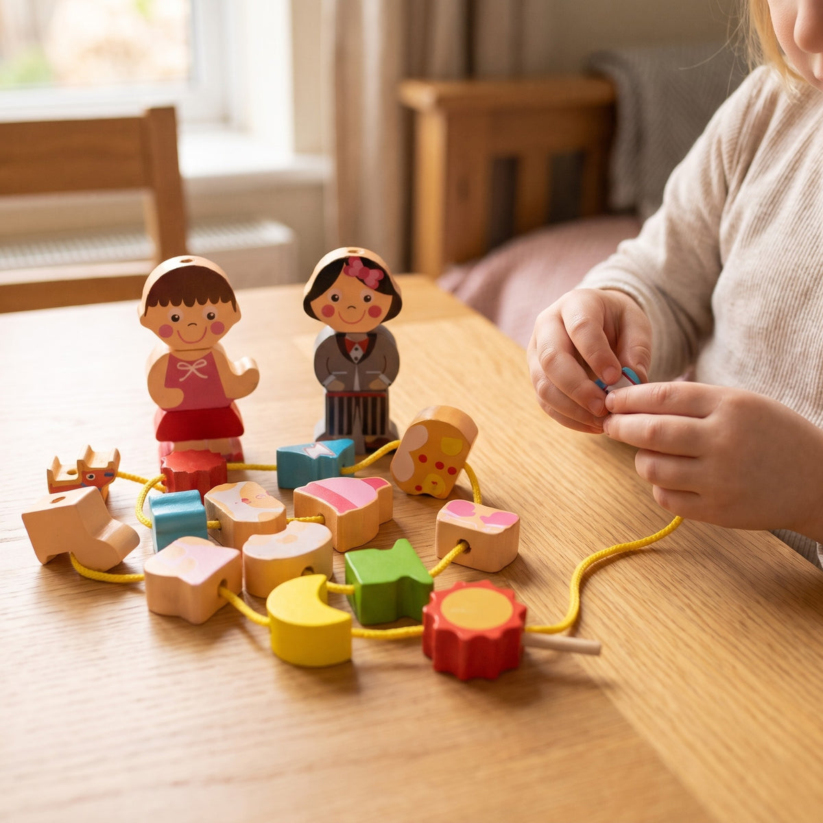 Child threading the wooden dress up character beads on an oak table