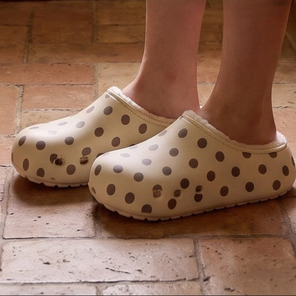Feet in cream polka dot clog slippers on a kitchen floor