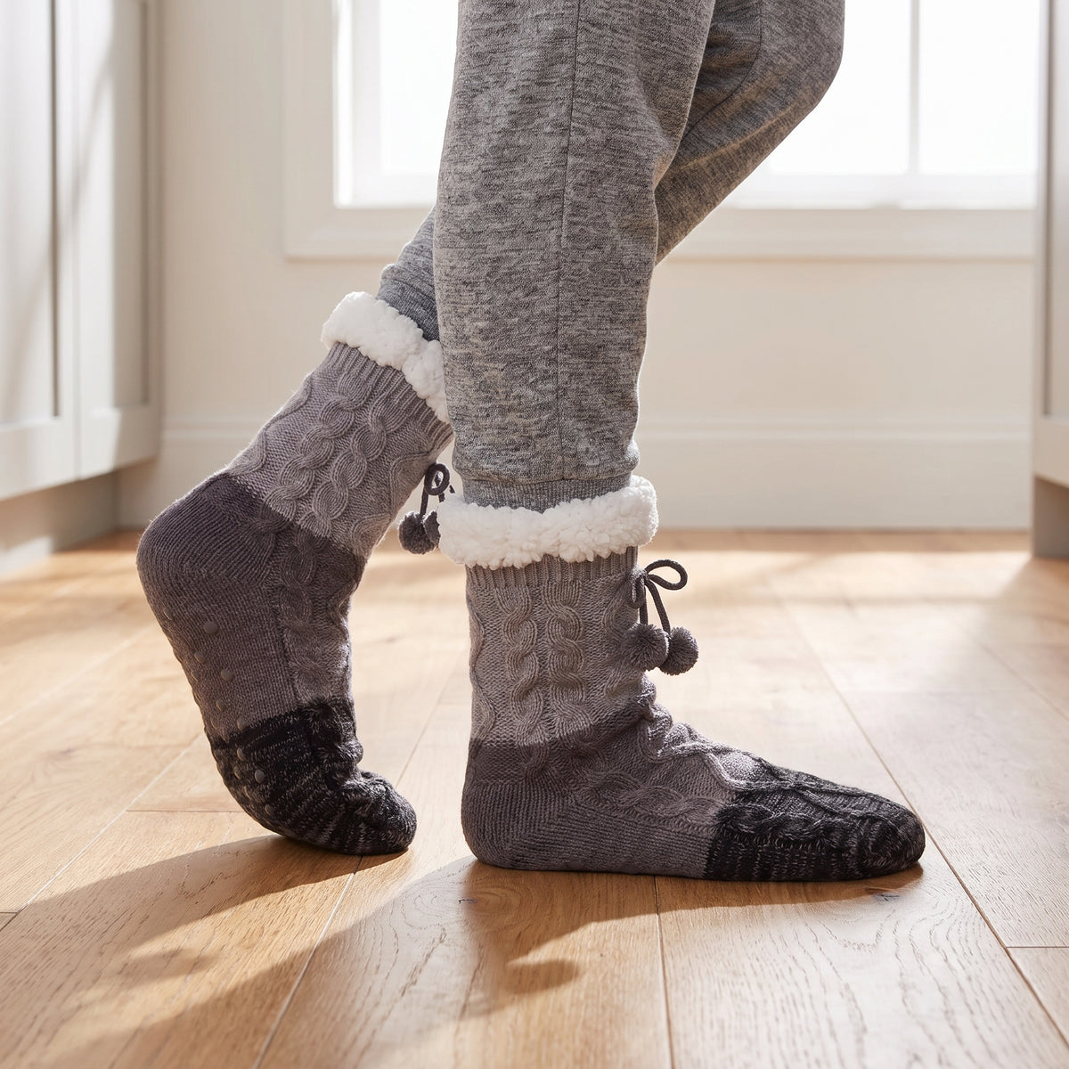 Grey non slip slipper socks with grip dots on a wooden floor