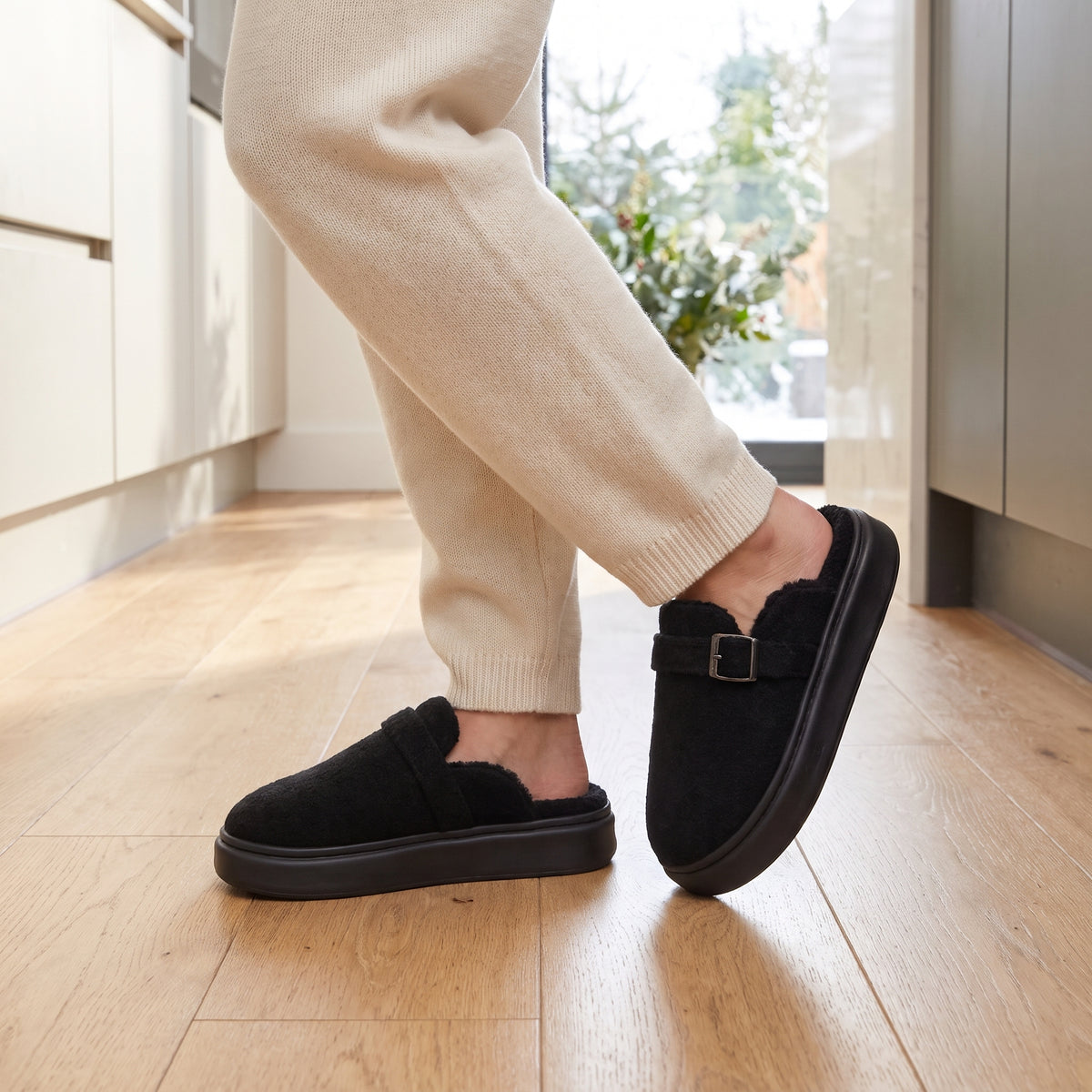 Woman in a kitchen wearing black teddy clog slippers