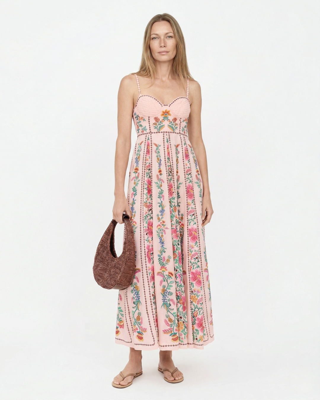 Woman wearing a floral dress holding a brown bag on a white background