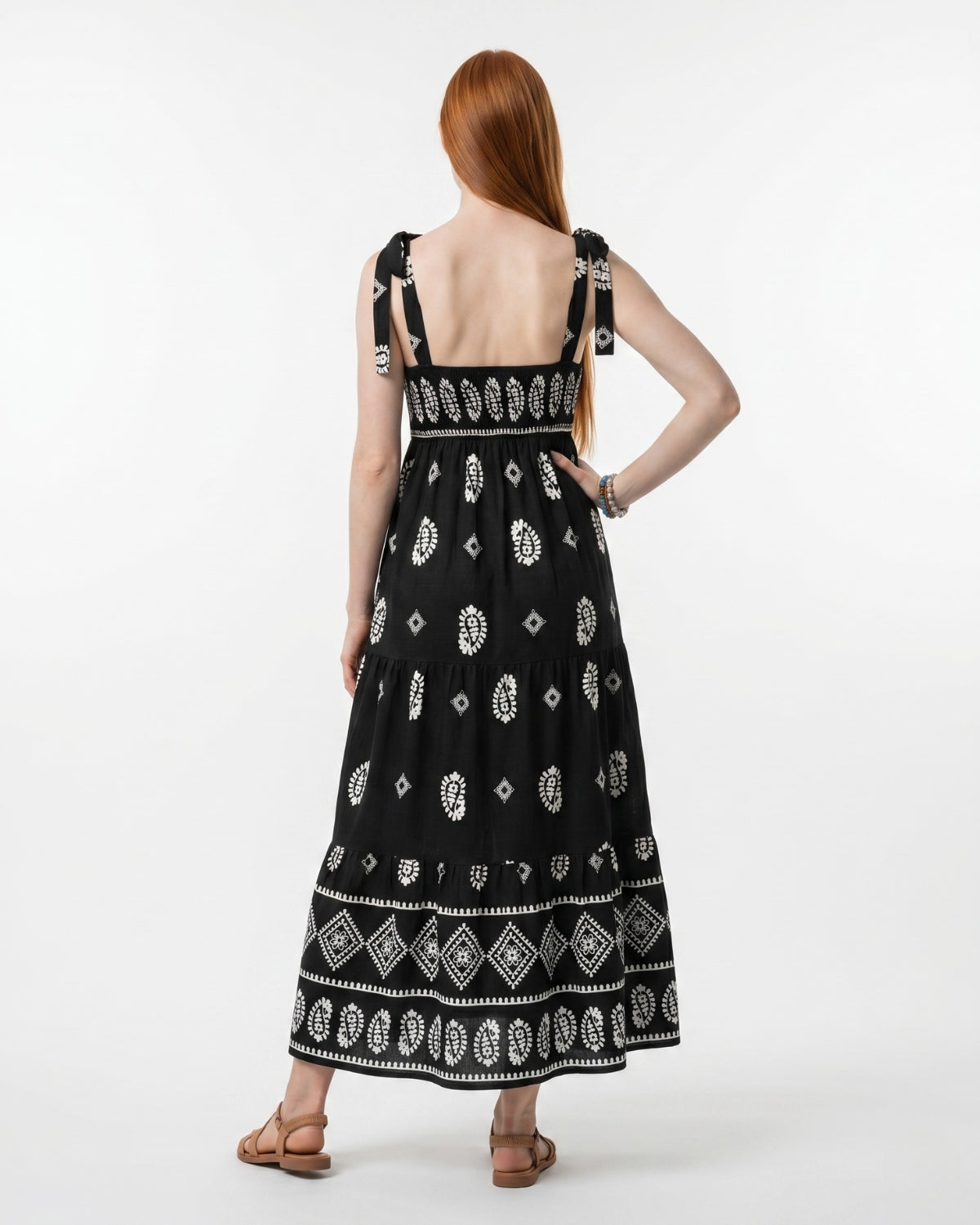 Woman wearing a black dress with white patterns on a white background