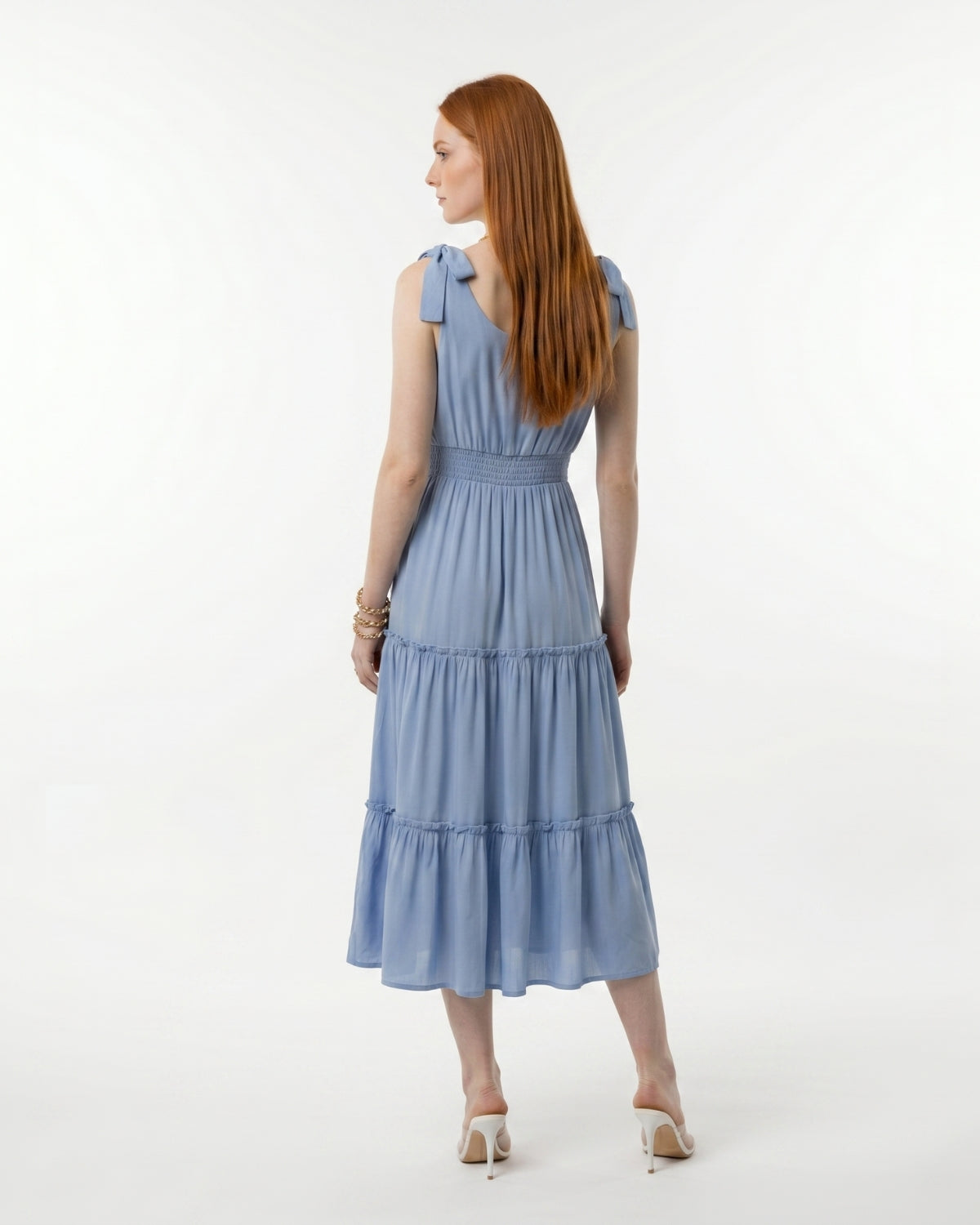 Woman wearing a blue dress with ruffled sleeves on a white background