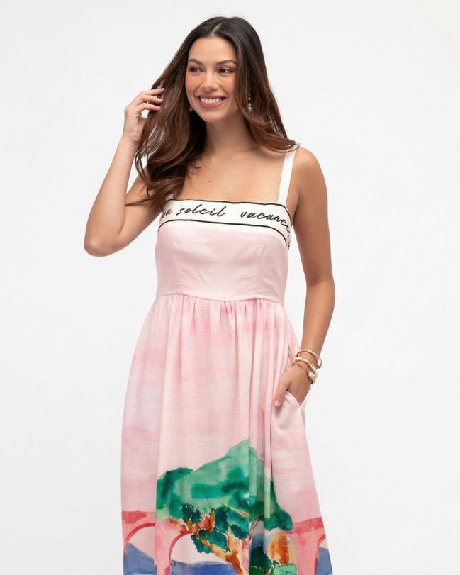Woman wearing a pink dress with a scenic print on a white background