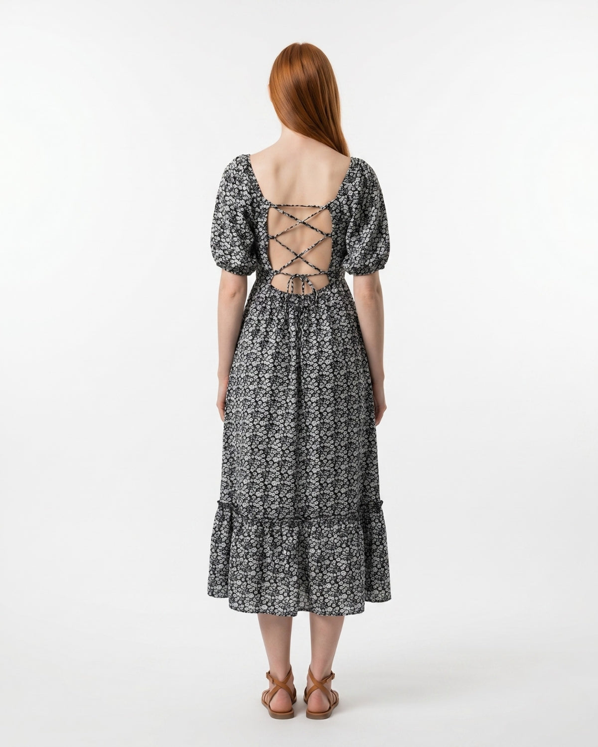 Woman wearing a black and white patterned dress with a lace-up back on a white background