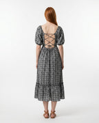 Woman wearing a black and white patterned dress with a lace-up back on a white background