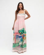 Woman wearing a pink dress with a scenic print on a white background