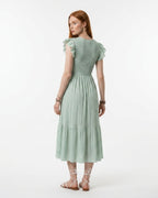 Woman wearing a light green dress with ruffled sleeves on a white background