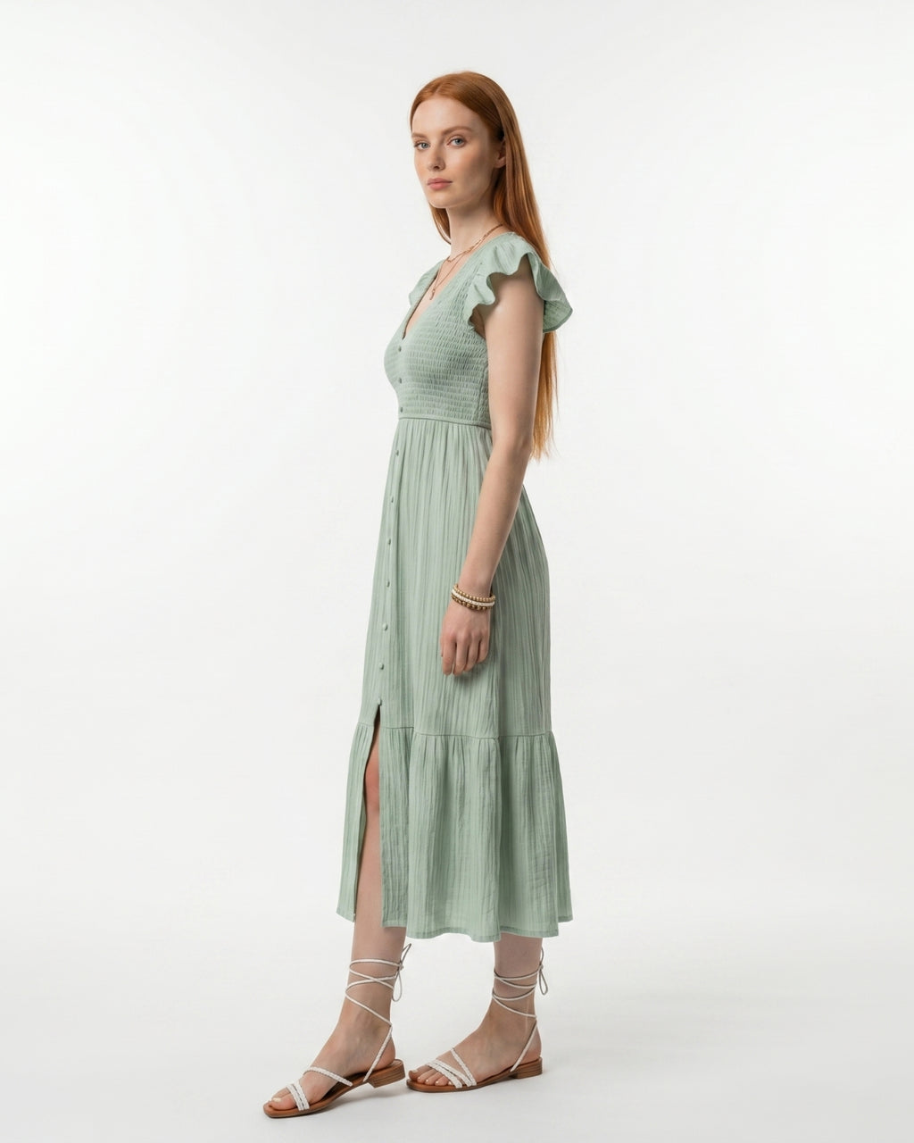 Woman wearing a light green dress with ruffled sleeves on a white background