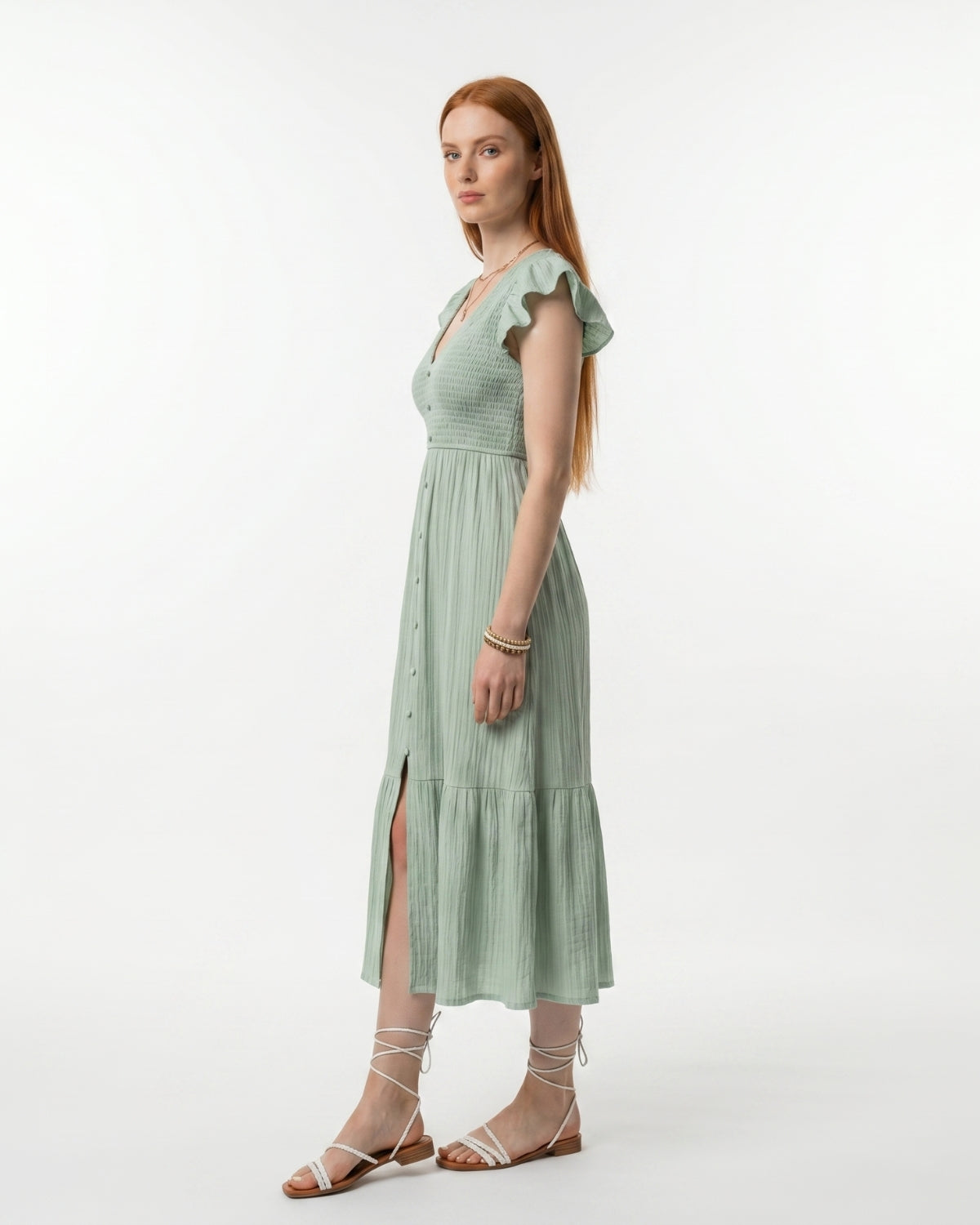 Woman wearing a light green dress with ruffled sleeves on a white background