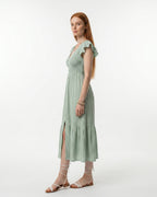 Woman wearing a light green dress with ruffled sleeves on a white background
