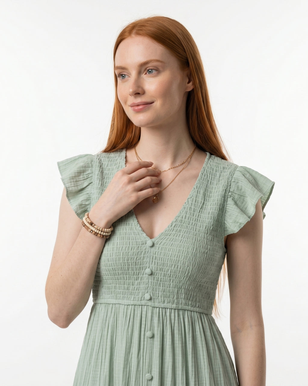 Woman wearing a light green dress with ruffled sleeves on a white background