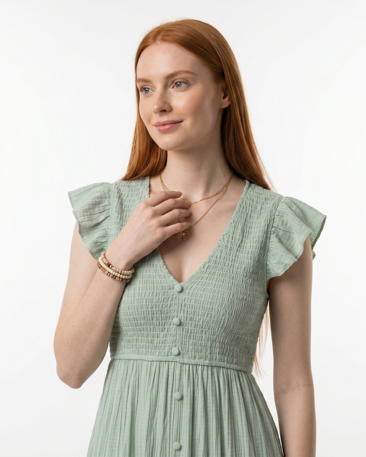Woman wearing a light green dress with ruffled sleeves on a white background