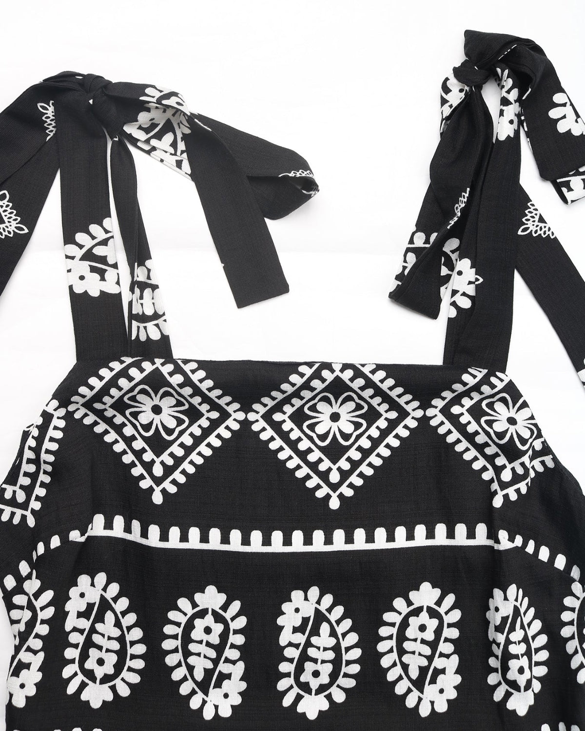 Black dress with white floral patterns and bow details on a white background