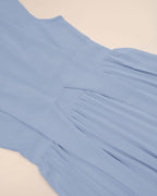 Light blue dress with pleated details on a beige background