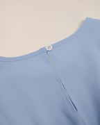 Close-up of a light blue garment with a button on a beige background