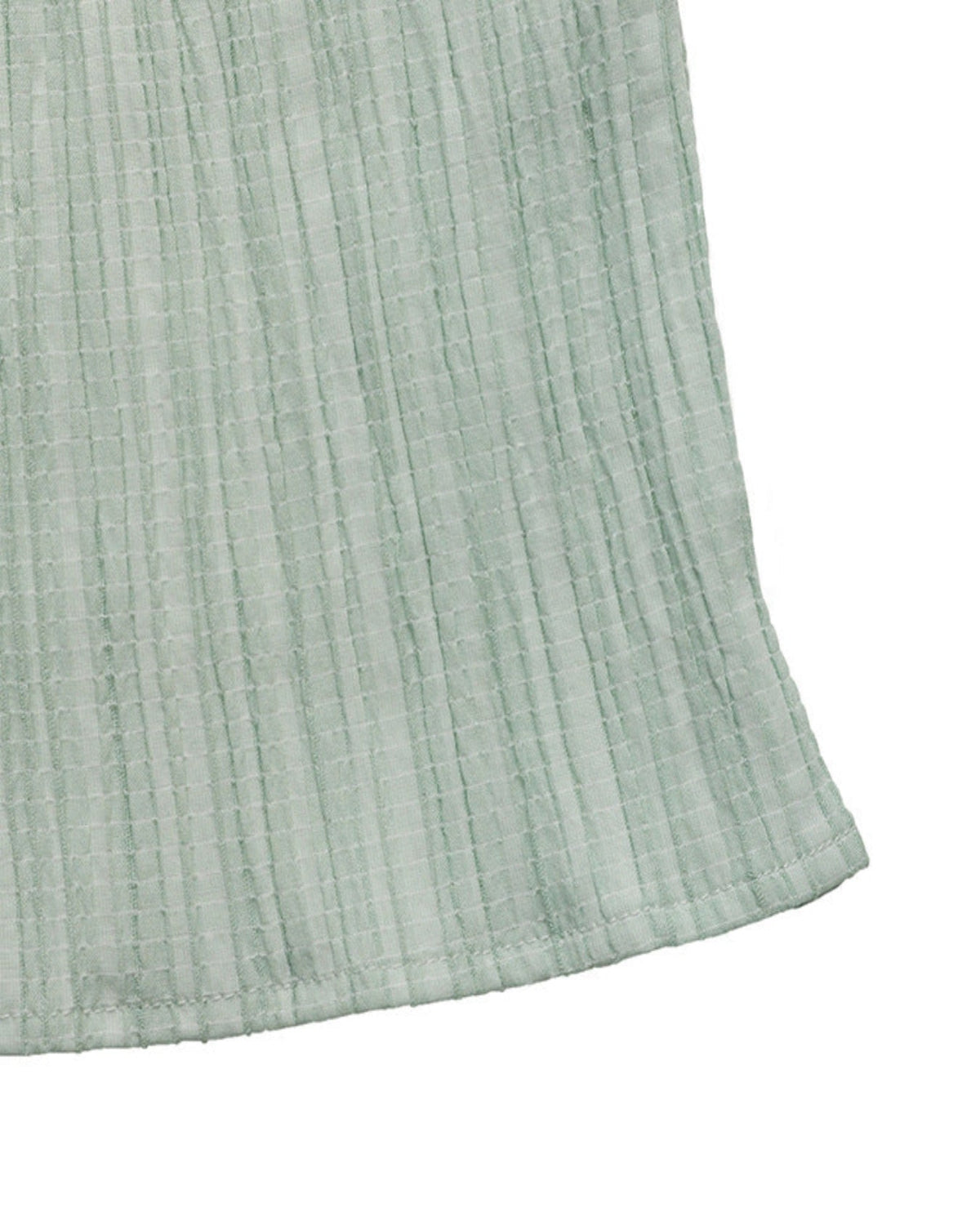 Close-up of a textured light green fabric corner on a white background