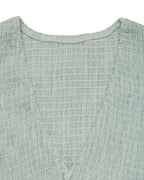 Close-up of a textured green garment with a white background