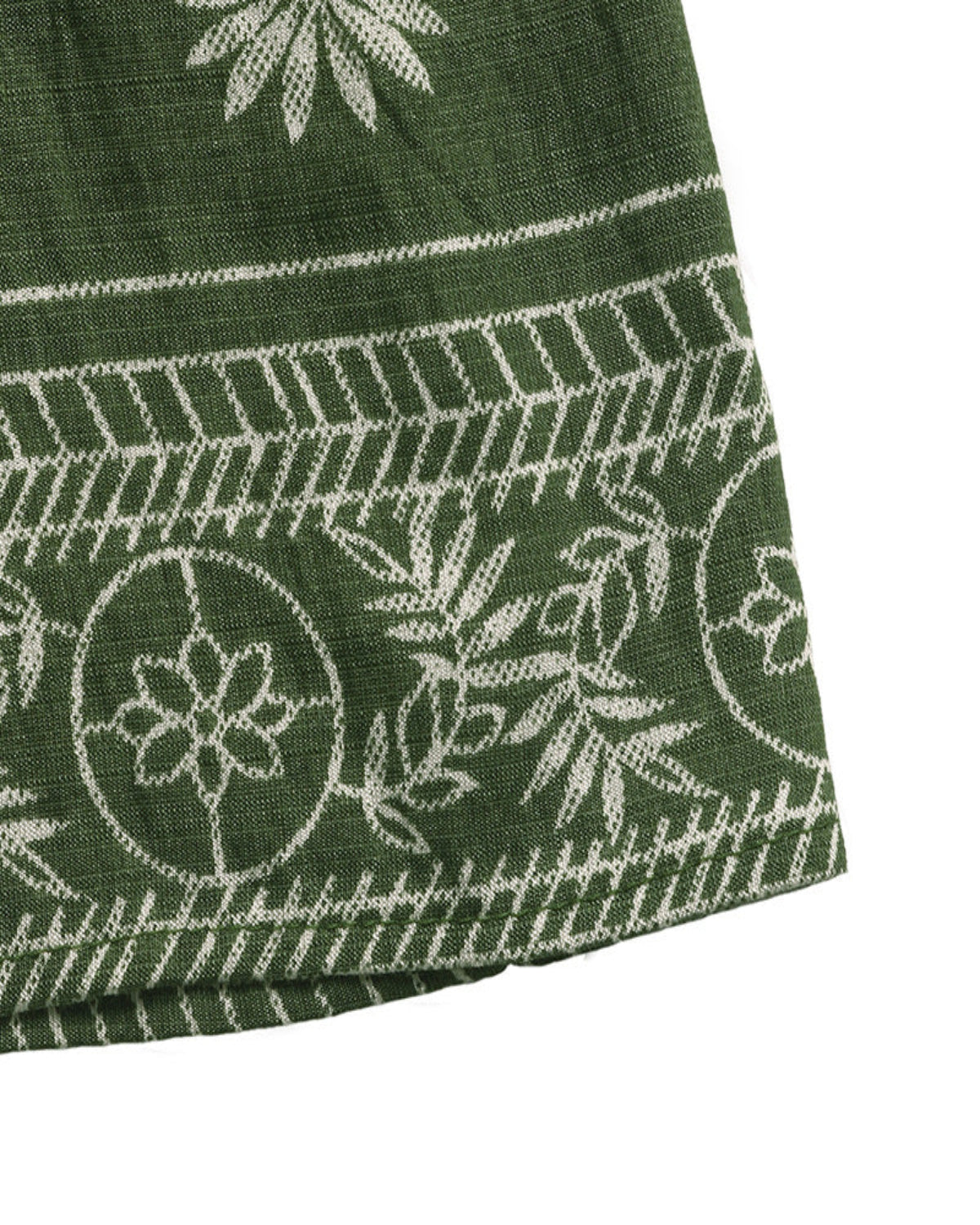 Close-up of a green fabric with white floral patterns on a white background