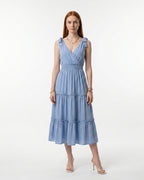 Woman wearing a light blue dress with ruffled straps on a white background