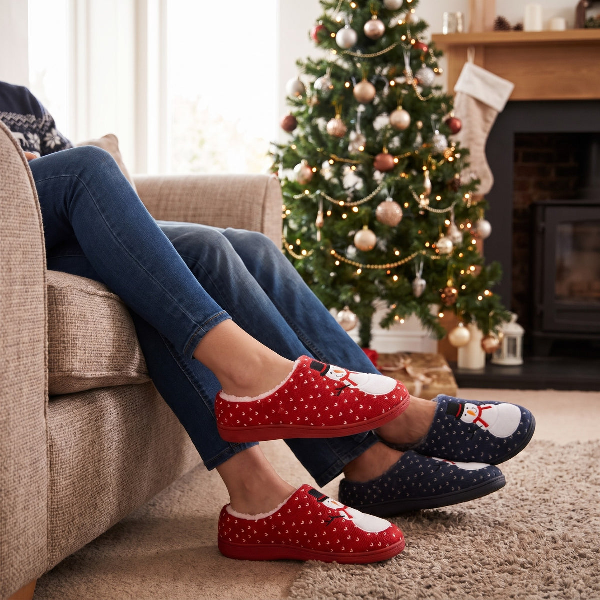 Couple by a Christmas tree wearing red and navy snowman slippers