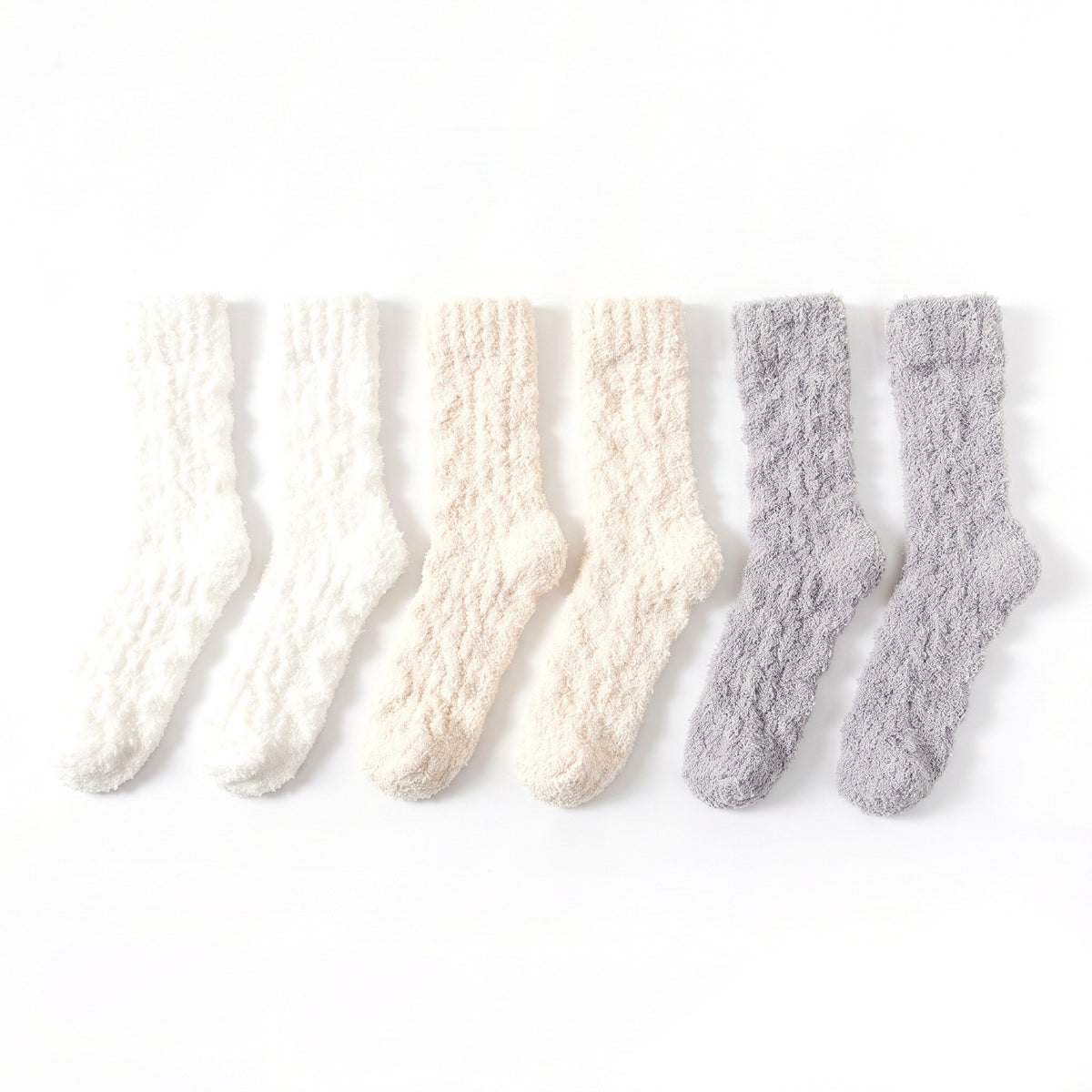 Three pairs of fluffy bed socks in white, cream and grey