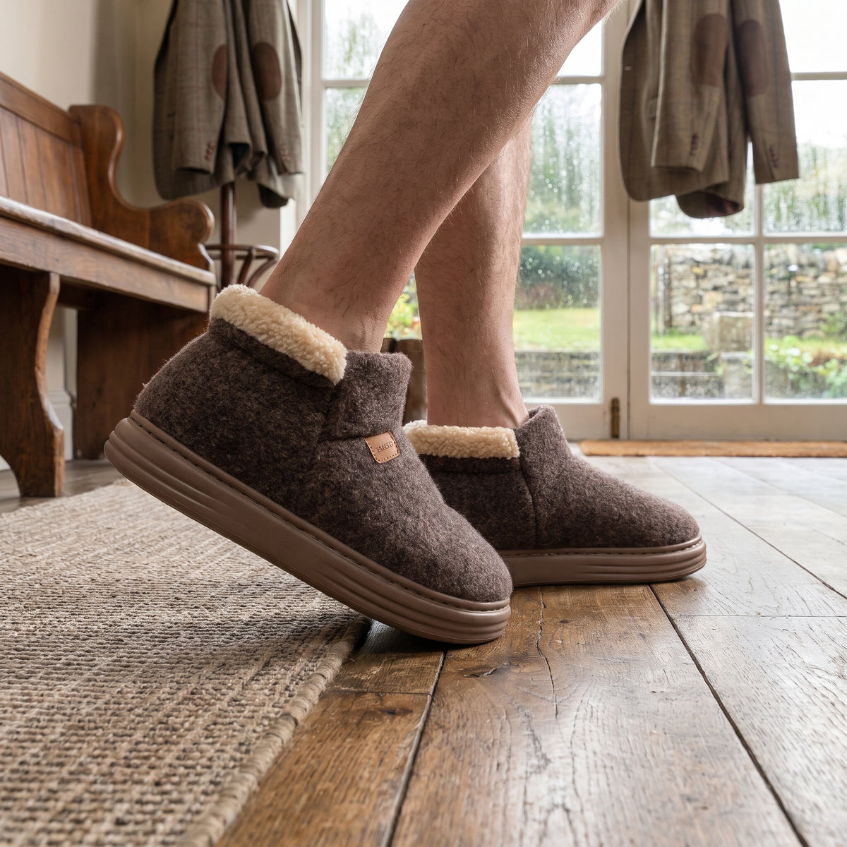 Coffee brown men's bootie slippers on oak floorboards in a hallway