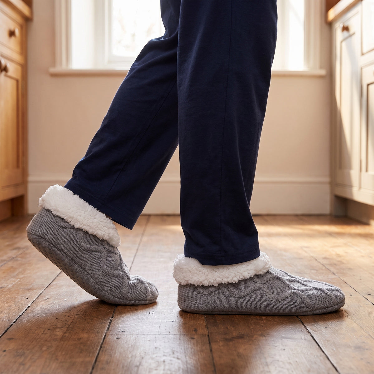 Man in a kitchen wearing grey non slip slipper socks
