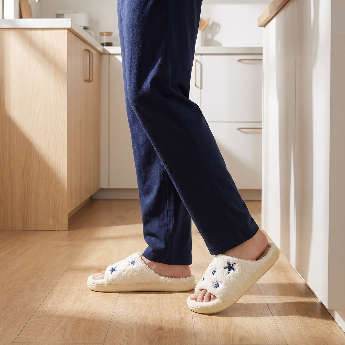 Man in navy pyjamas wearing cream star slippers in a kitchen