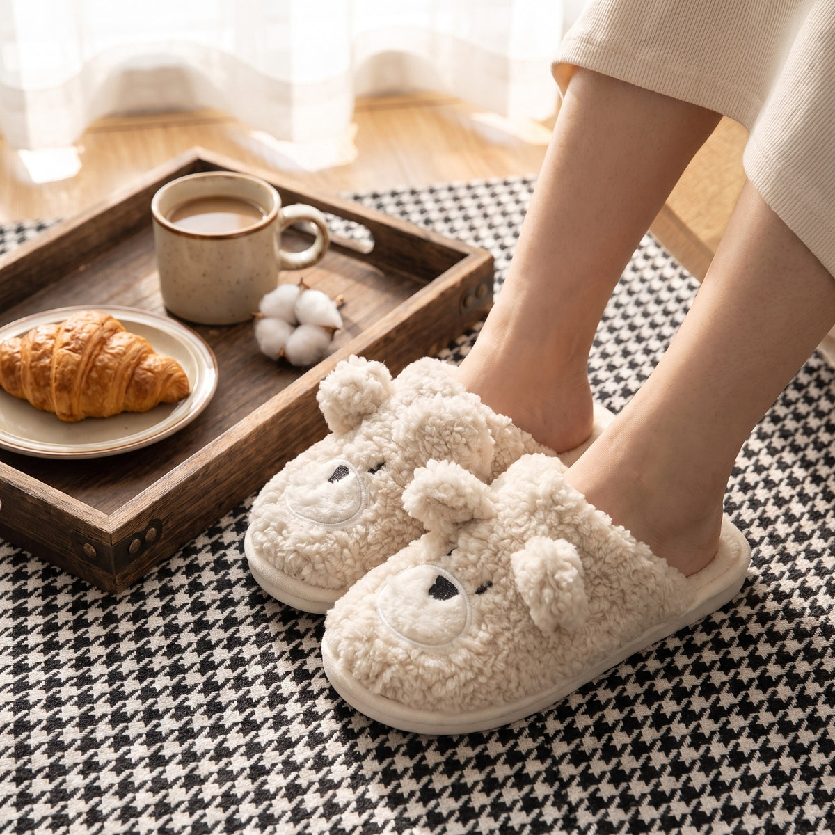 Woman wearing cream teddy bear slippers beside a breakfast tray