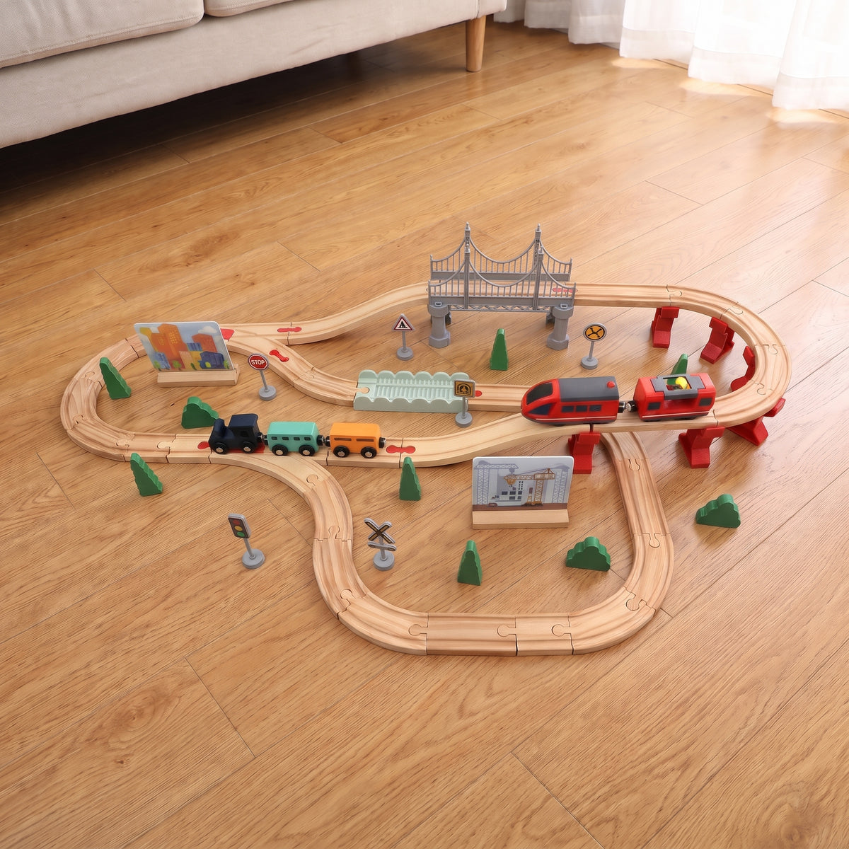 Large wooden train track layout with grey bridge on a wooden floor